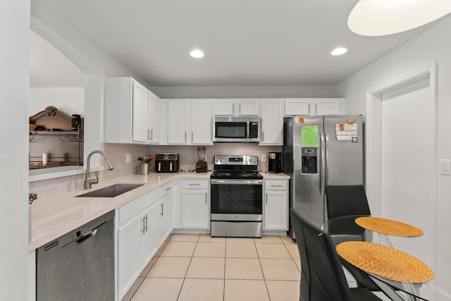 kitchen featuring light tile patterned floors, sink, backsplash, white cabinetry, and appliances with stainless steel finishes