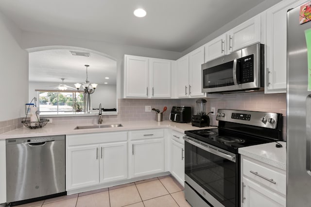 kitchen featuring light tile patterned flooring, sink, ceiling fan with notable chandelier, white cabinetry, and appliances with stainless steel finishes