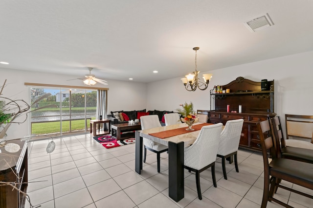 tiled dining area with ceiling fan with notable chandelier and a water view