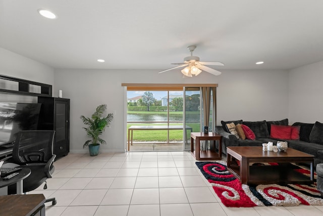 tiled living room with ceiling fan and a water view