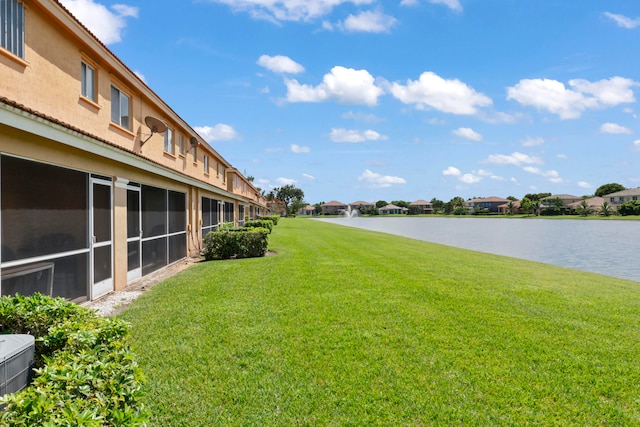 view of yard with a sunroom and a water view