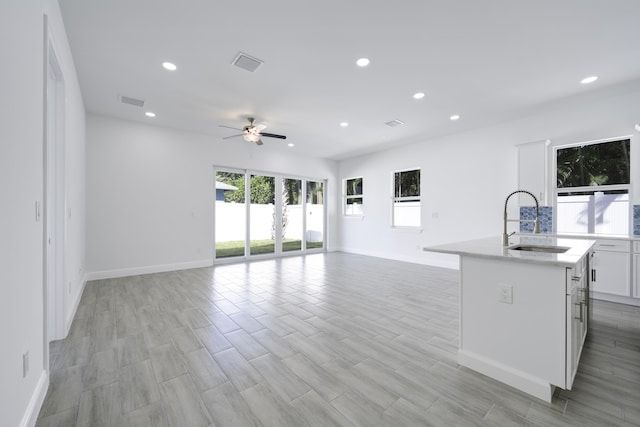 kitchen featuring a wealth of natural light, a kitchen island with sink, ceiling fan, and light wood-type flooring