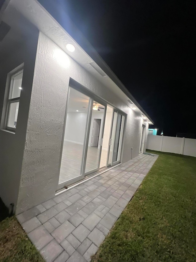 property exterior at night with a patio area and a yard