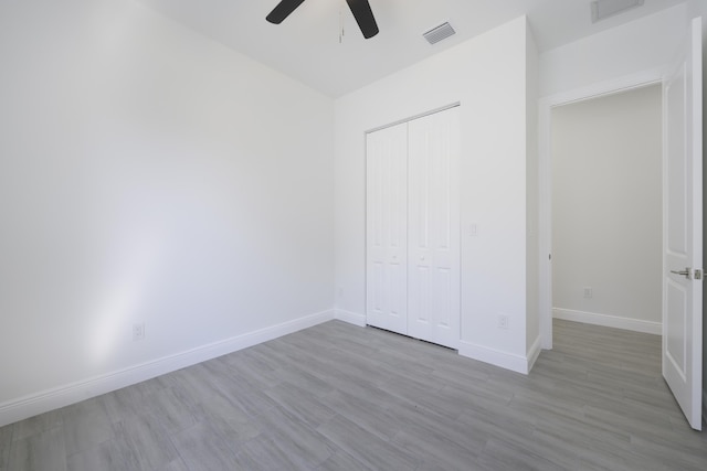 unfurnished bedroom with ceiling fan, light wood-type flooring, and a closet