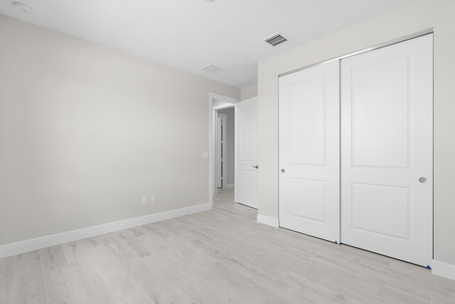 unfurnished bedroom featuring light hardwood / wood-style flooring and a closet