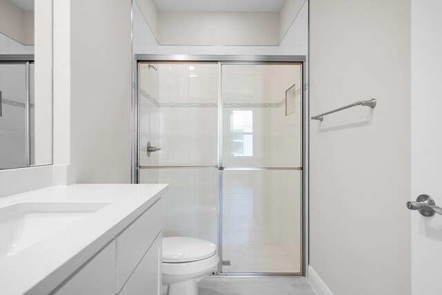 bathroom featuring vanity, toilet, and a shower with door