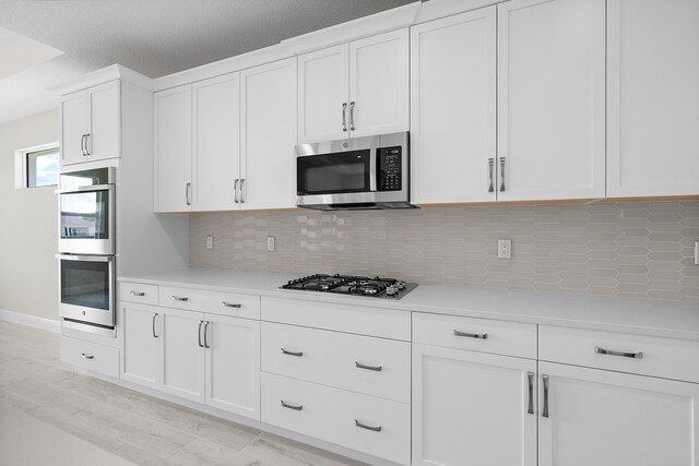 kitchen featuring white cabinets, a textured ceiling, appliances with stainless steel finishes, and tasteful backsplash