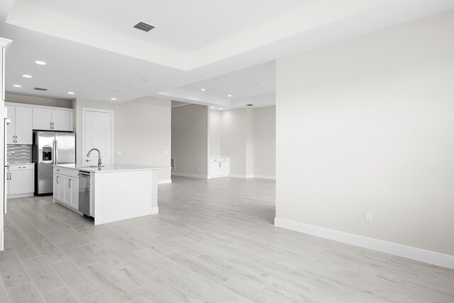 kitchen with stainless steel appliances, white cabinetry, a center island with sink, and sink