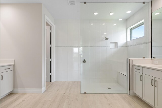 bathroom with vanity, hardwood / wood-style floors, and tiled shower