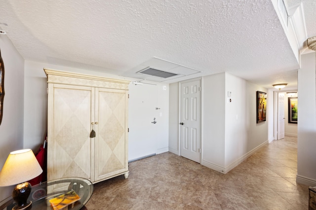 corridor with a textured ceiling and light tile patterned floors