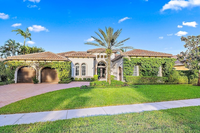 mediterranean / spanish house with a garage and a front lawn