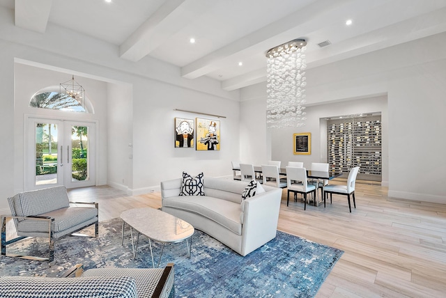 living room featuring beamed ceiling, light hardwood / wood-style flooring, french doors, and a notable chandelier