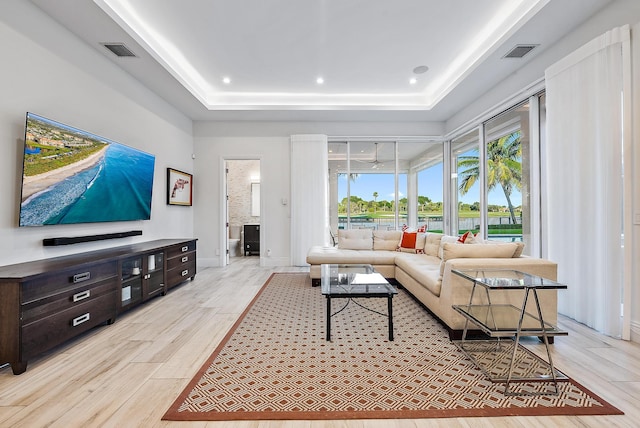 living room featuring a tray ceiling and light hardwood / wood-style floors