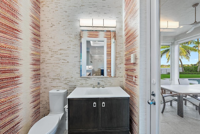 bathroom featuring tile walls, vanity, and toilet