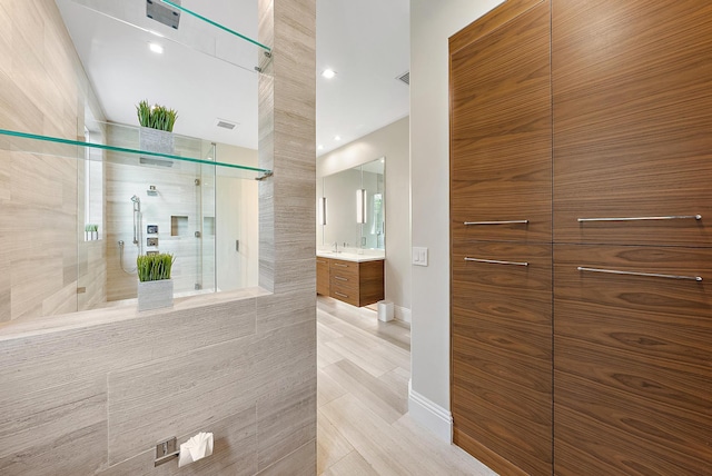 bathroom with tile walls, vanity, and a shower with shower door