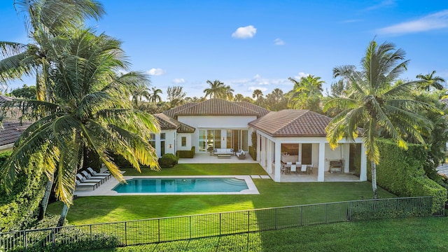 rear view of property with a patio, a yard, and a fenced in pool