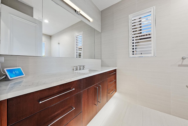 bathroom featuring a shower, tile walls, backsplash, vanity, and tile patterned floors