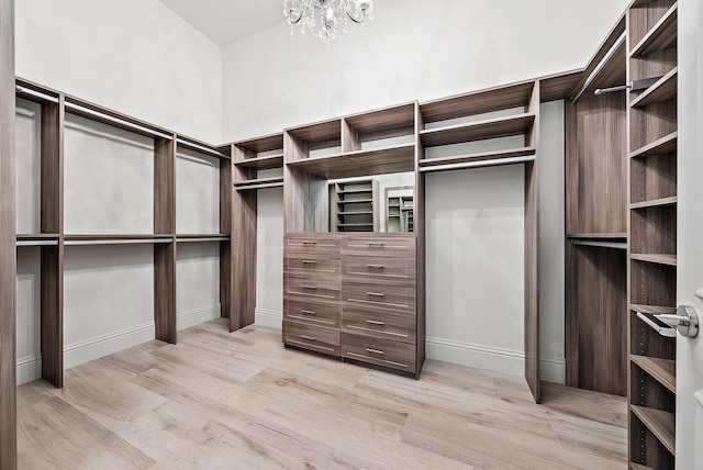 spacious closet with light wood-type flooring and a chandelier