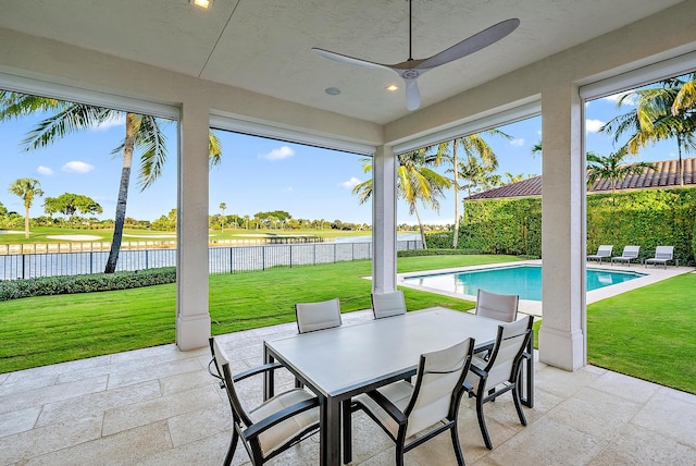 view of patio with a fenced in pool, a water view, and ceiling fan