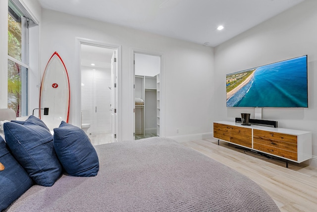 bedroom with light hardwood / wood-style floors, a spacious closet, ensuite bathroom, and a closet