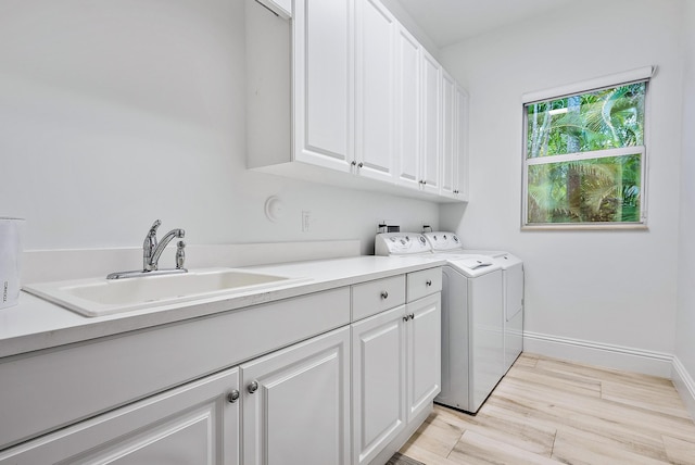 laundry room with cabinets, light hardwood / wood-style flooring, washer and dryer, and sink