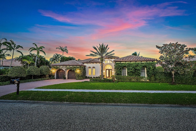 mediterranean / spanish house featuring a lawn and a garage