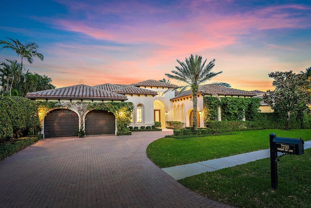 mediterranean / spanish house featuring a garage and a yard