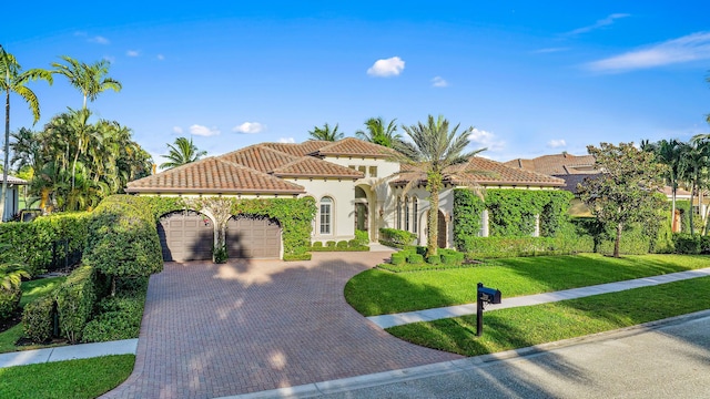 mediterranean / spanish-style home featuring a garage and a front lawn