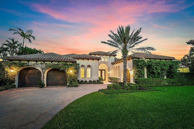 mediterranean / spanish home featuring a garage and a yard