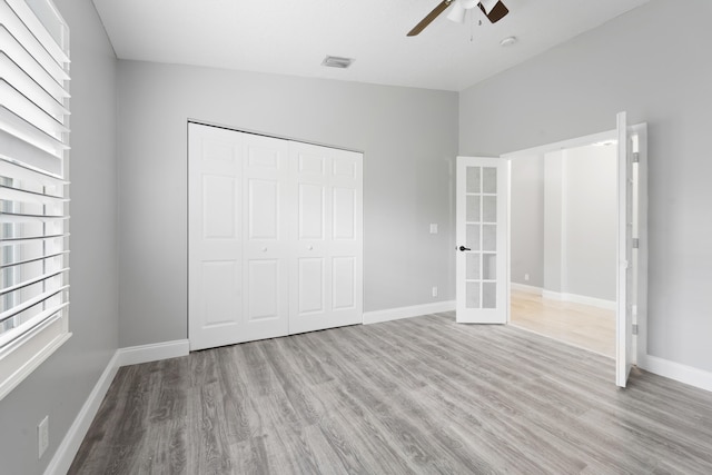 unfurnished bedroom featuring ceiling fan, a closet, light wood-type flooring, and vaulted ceiling