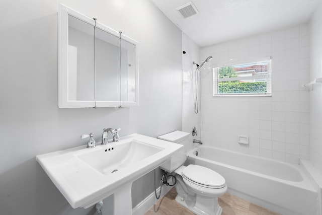 full bathroom featuring tiled shower / bath combo, toilet, and sink