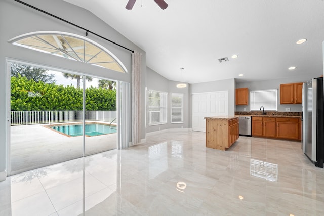 kitchen with ceiling fan, lofted ceiling, sink, a kitchen island, and appliances with stainless steel finishes