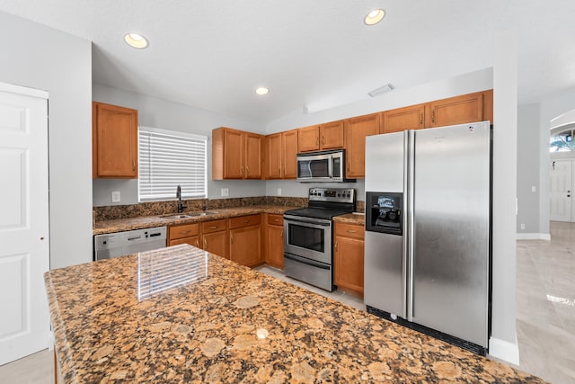 kitchen with lofted ceiling, sink, a textured ceiling, stainless steel appliances, and dark stone countertops