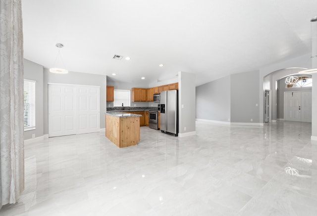 kitchen featuring pendant lighting, stainless steel appliances, sink, and a kitchen island