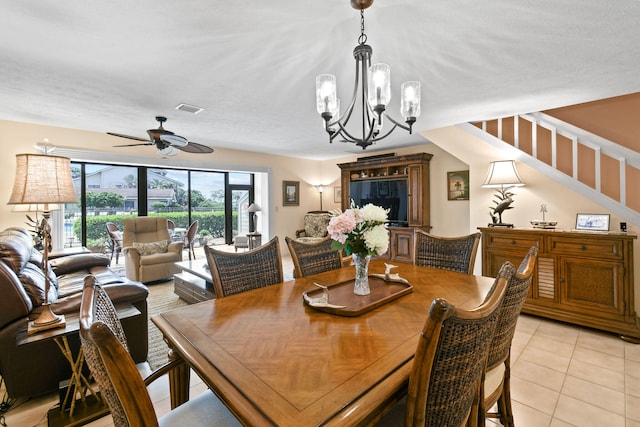 dining space with light tile patterned floors and ceiling fan with notable chandelier