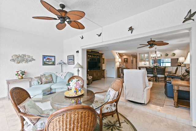 tiled living room featuring ceiling fan with notable chandelier and a textured ceiling