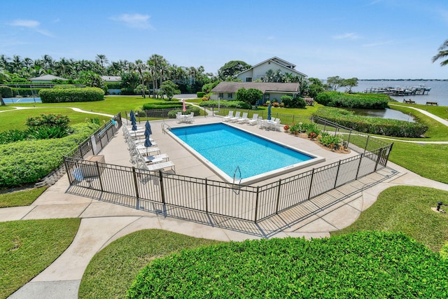 view of swimming pool with a yard, a water view, and a patio area