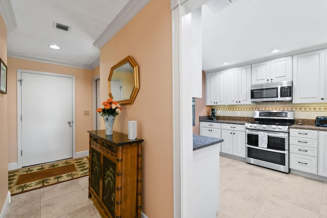 kitchen with white cabinets, stainless steel appliances, crown molding, and light tile patterned flooring