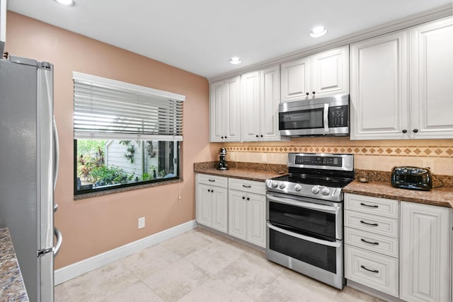 kitchen with light tile patterned flooring, dark stone countertops, decorative backsplash, white cabinets, and appliances with stainless steel finishes