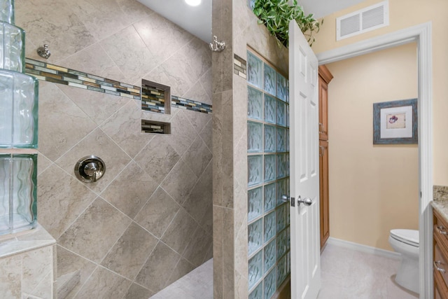 bathroom with tile patterned flooring, vanity, toilet, and a tile shower