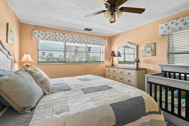 bedroom with ceiling fan and a textured ceiling