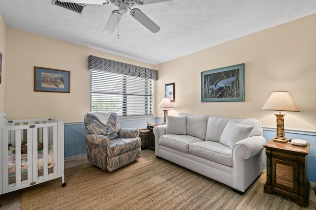 living room featuring ceiling fan and a textured ceiling