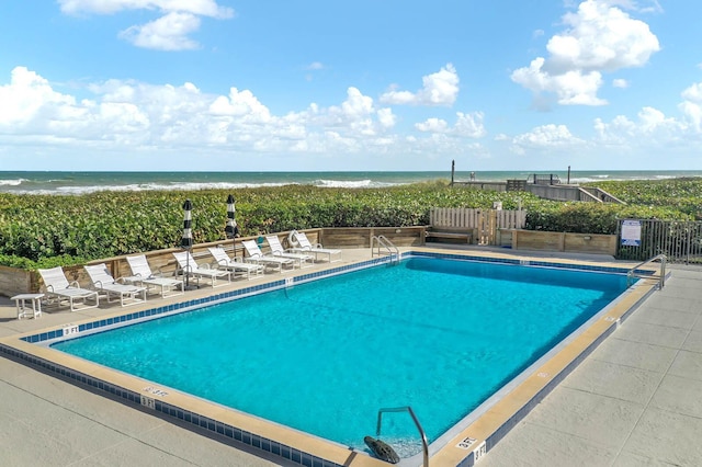 view of pool featuring a water view and a patio