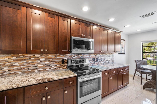 kitchen featuring light stone countertops, appliances with stainless steel finishes, light tile patterned floors, and decorative backsplash