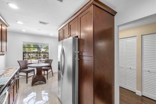 kitchen featuring appliances with stainless steel finishes, light stone counters, and light wood-type flooring