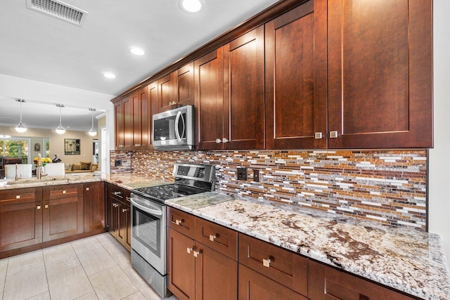 kitchen with light stone counters, stainless steel appliances, kitchen peninsula, decorative light fixtures, and backsplash