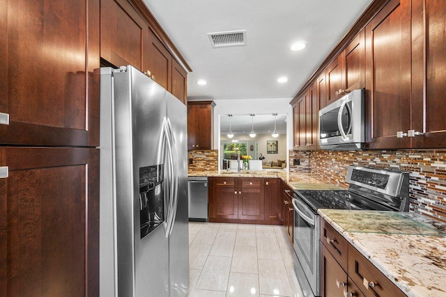 kitchen featuring decorative backsplash, pendant lighting, light stone counters, stainless steel appliances, and kitchen peninsula