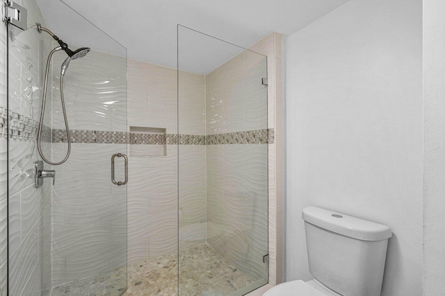 bathroom featuring a shower with shower door and toilet