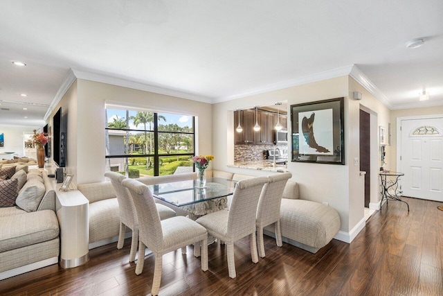 dining space with crown molding, sink, and dark hardwood / wood-style flooring