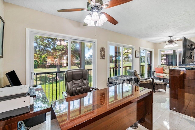 interior space featuring ceiling fan, light tile patterned flooring, and a textured ceiling